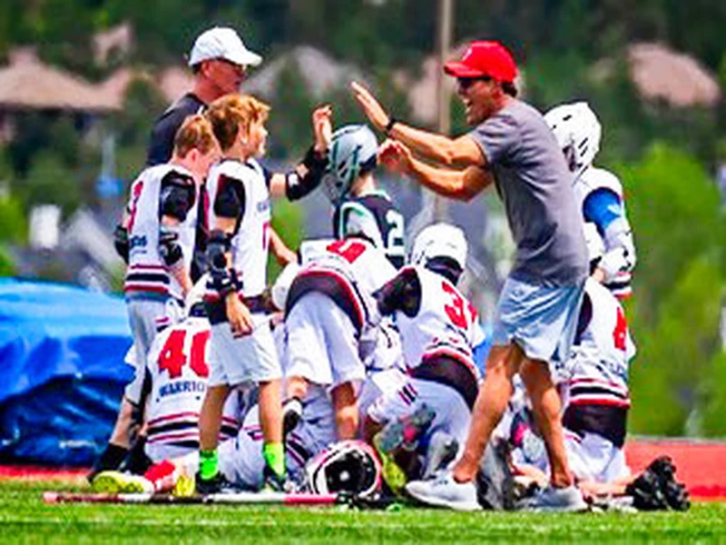 A Greater Good Lacrosse coach encouraging youth players during a team huddle
